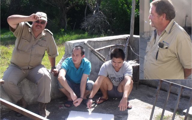 DAFF Inspekteur Hennie Smit van DAFF hou toesig oor die twee Chinese verdagtes. Inlas: Johan Rademeyer.