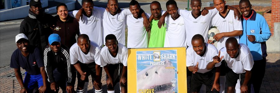 Masakaneâ€™s Eastern Cape United soccer team played in the local league for the past two seasons.  In the first season, the team finished 14th out of 17 teams and in the second season bettered itself to a number seven position. They were privileged to receive brand new outfits from White Shark Projects (WSP) previously.  Natasha Smith from WSP appears here with Mandlonke Ngazini (middle) who initiated the sponsorship and who is working at WSP for the past thirteen years.  Mr Ngazini said that the main objects are to keep the youth off the streets and to fight against drug abuse through healthy sport participation.  He thanked White Shark Projects for the generous sponsorship.  Anyone interested in participating in any of Eastern Cape Unitedâ€™s team efforts can contact the Chairperson, Mr Mhlaba at 0735771207.