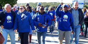 DA-leiers tydens â€˜n vreedsame optog saam met die Wes-Kaapse Premier, Helen Zille met singende en dansende ondersteuners van Masakhane agter hulle.  Voor vlnr is  Rdl Dudley Coetzee (Wyk 11),  Helen Zille,  Masizole Mnqasela (Lid van die Provinsiale Parlement),  Andrew Komani (Wyk 1)  en  dr. Michael Cardo (Lid van die Parlement).