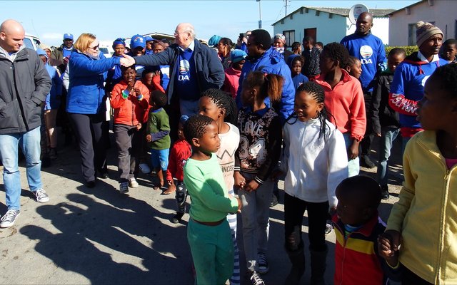 Selfs kinders het opgewonde en al dansende aan Premier Helen Zille se optog in Masakhane se strate deelgeneem. Tweede van links gee Premier Zille en Rdl Dudley Coetzee mekaar â€˜n handdruk.