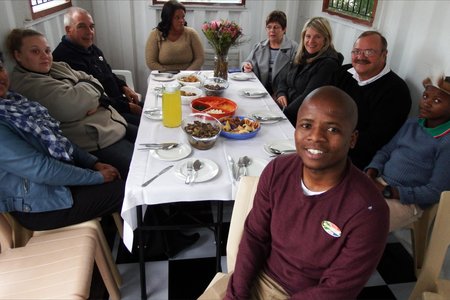 Regs voor sit â€˜n trotse Ally Msweli tydens die amptelike opening van sy eie toerbedryf in Masakhane, Masakhane Township Tours, saam met van die gaste wat die opening bygewoon het.