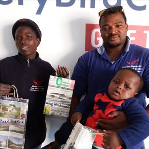 Vlnr is Njongo Mlimisi en Xolani Lawo (Bestuurder: APSS) met sy eenjarige seuntjie, Akum, wat hier spog met sy bewaringsinkopiesak.