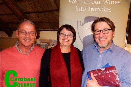 Die aanbieder tydens Gansbaai Wynproegilde se wynproe aand, Andre Rheeder (regs) staan met sy  Wynproegilde voorskoot wat deur klublede Steve Serbon en Anne-Mare de Witt aan hom oorhandig is.