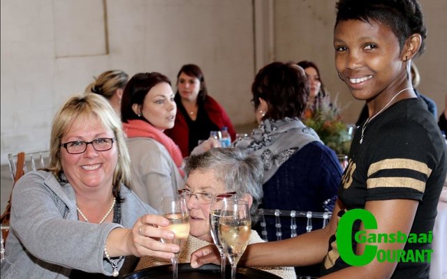 Mandy Phillips (regs) bedien vonkelwyn aan Ria van der Merwe van Kleinbaai.  AdÃ©le Eksteen sit agter.