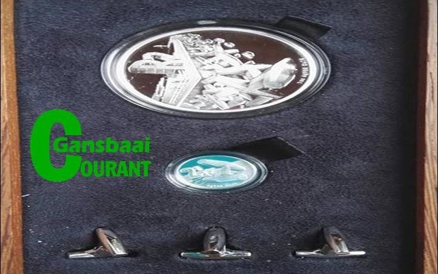 Die gemonteerde R2 en 2Â½c silwermuntstukke, met dolosafdrukke daarop, waarmee Aubrey Kruger enkele weke voor sy afsterwe deur die Suid-Afrikaanse Munt vereer is.  