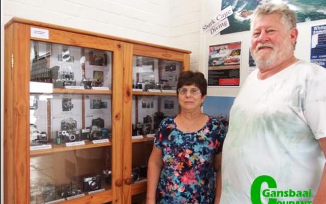 â€˜n Veteraan kamera-uitstalling in Gansbaai Toerisme se uitstallingslokaal wat die moeite werd is om te besoek. Vlnr Glenda Kitley (Bestuurder: Gansbaai Toerisme) en die uitstaller, John McGregor.