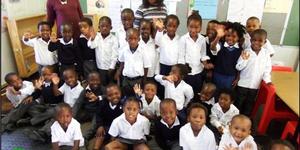 Masakhane Primary School se 52 graad Râ€™e het ook aanvanklik aan hul kospakkies vasgeklou met die neem van die foto. Agter links is Ellen Pato (Gr R.a) en regs is Xoliswa Hoza (Gr R.b).