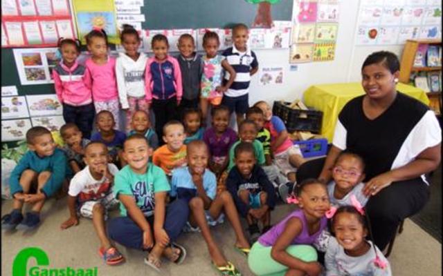 Gansbaai PrimÃªr in Blompark se 60 graad Râ€™e het met moeite afstand gedoen van hul kospakkies met die neem van die foto. Regs sit Karen Benjamin (Gr R.2). Helena Slammat (Gr R.1) was afwesig met die neem van die foto.