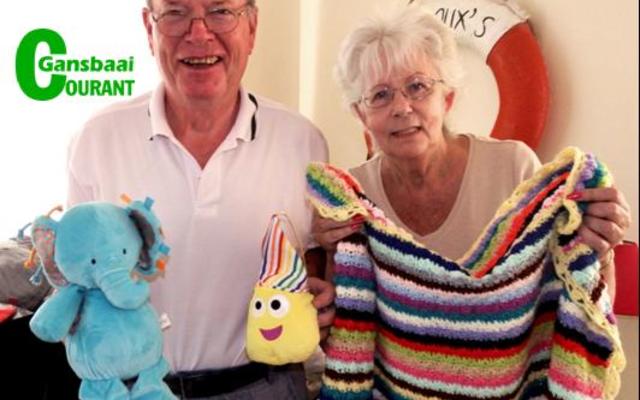 Jack Doyle en sy eggenote, Anita, wat Gansbaai jaarliks besoek om hul liefdadigheidswerk uit te voer.  Hier staan die egpaar by 6 enorme groot reissakke propvol warm klere, sagte speelgoed en verskeie ander items wat gedurende Maart vanjaar aan skoolkinders oorhandig sal word.