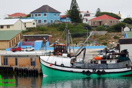 Die foto vertoon â€˜n deel van die area in Gansbaai hawe waar â€˜n man van Walvisbaai verdrink het. In die agtergrond kan die geskiedkundige â€œBlou Huisâ€ bokant die hawe gesien word wat gedurende die naweek onder â€˜n inbraak deurgeloop het.