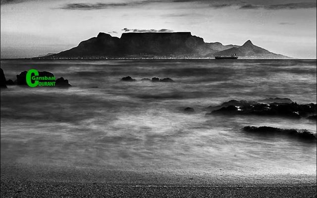 Nog â€˜n besonderse foto deur Robert Johnson, Gansbaai Fotografieklub se opleidingsfotograaf, met â€˜n wasige (blurred) oseaan op die voorgrond en â€˜n duidelike beeld van Tafelberg en â€˜n boot op die agtergrond. 