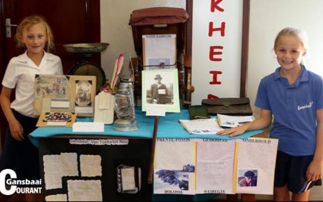 Die graad 4's van Laerskool Gansbaai het verlede week 'n uitstalling oor die geskiedenis van die dorp in die skoolsaal gehou. Nicole Schutte (links) en Elani Halleen het saamgespan. Behalwe vir die kapkarretjie, ou skeermes en possak, het almal die foto waarop hulle juffrou, Heidi Chivell as jong onderwyseres baie amusant gevind. Die foto is 38 jaar gelede geneem toe Heidi in Gansbaai begin skoolhou het. 
