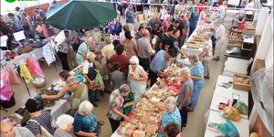 â€˜n Geheelbeeld van die gesellige basaar, met stalletjies in die sy-saal en buite op die terein.
