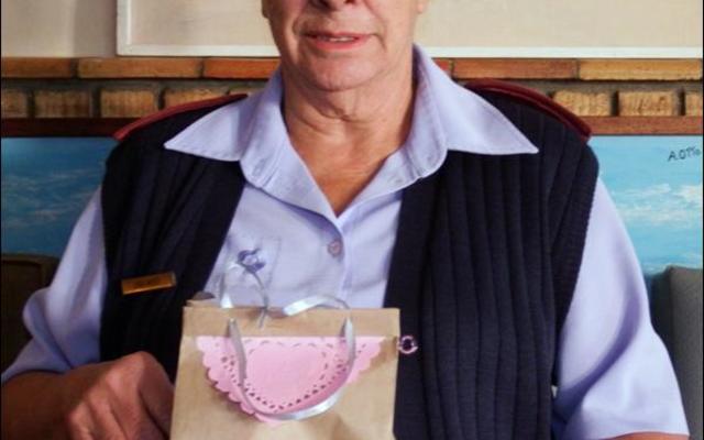 Suster Linda Meyer (75), afgetrede bestuurder van HaS vir meer as 20 jaar, staan met haar kleurvolle geskenkpakkie van Gansbaai Goue Hande wat sy ontvang het.