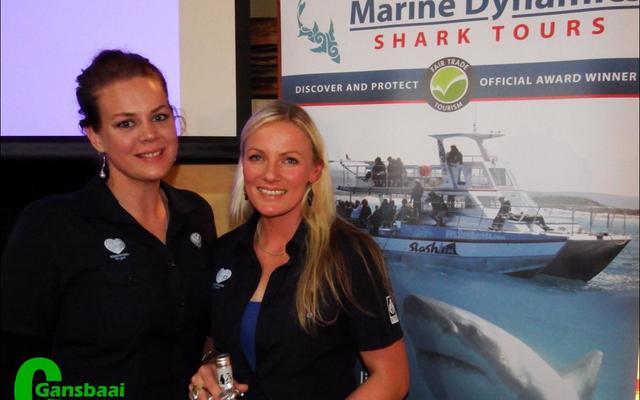 Alison Towner (right), white shark biologist for the Dyer Island Conservation Trust,  receives a bottle of wine after enlightening guests at the recent Marine Evening in the Great White House. With her is Cari du Preez, Marketing Manager.