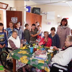 Links sit tannie Zellie Rock en regs tannie Rona Smit, wat ook eers drukkies ontvang het en daarna vrugte. Alanda Brown staan regs agter.