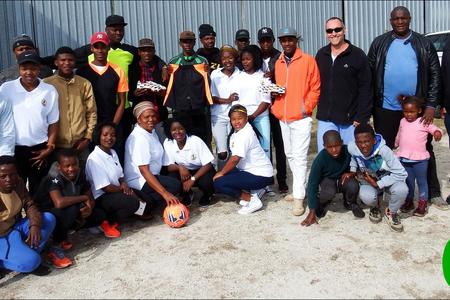 Solyx United sokkerspan glimlag breed oor hul nuwe uitrustings en sokkerballe, geborg deur Solyx Films SA. Van regs is Jacques van Lill (ontwikkelingsprogram), Thebelani Xovula (voorsitter) en Peter Huyser van Solyx Films, met â€˜n groepie kinders wat reeds die sokkerballe â€œingewyâ€ het.