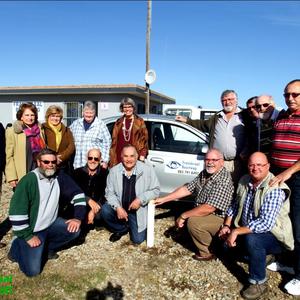 â€˜n Groep van die opgewonde patrollielede van Franskraal Buurtwag tydens die opening van hulle beheerkamer voor een van hulle patrollievoertuie.