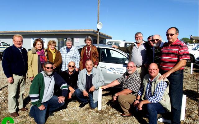 â€˜n Groep van die opgewonde patrollielede van Franskraal Buurtwag tydens die opening van hulle beheerkamer voor een van hulle patrollievoertuie.
