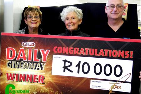 Dis mos hoe â€˜n R10 000 glimlag moet lyk. Claudette Barnes ontvang haar prys van Corrie Kotze, Defy se verteenwoordiger (links). Bayview Meubels se eienaar, Jan Barnard (regs) glimlag heel tevrede.