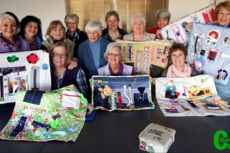 Die groep dames van Overberg Kwiltersgilde tydens een van hulle werksessies, waarvan sowat 8 van hulle â€œvroetelkombersiesâ€ gemaak het wat deur Alzheimerlyers benut kan word. Voor van links Nettie le Roux, Olga Kuschke (voorsitter) en Yvonne Joubert. Agter van links Grietjie Meyer, Alda Rowan, Margarette Clarens, Adri Wessels, Hettie Lass, Suzette Reineke, Mansie Pienaar, Carol McKenzie en Christel Sprong.  