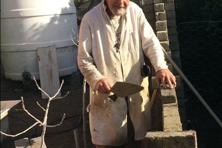 Oom Koos Groenewald waar hy besig om die muur agter sy huis klaar te bou. Hy het sy hele huisie waar hy nou rustig woon, eiehandig sonder hulp gebou.