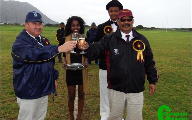 Die twee skoolhoofde, mnr Wilfred Taylor (links) van HoÃ«rskool Eben DÃ¶nges en mnr Tommy Wilson van Gansbaai Academia klink â€˜n glasie sjampanje voor die hoofwedstryd. Agter hulle is die sjampanje-nooi, Anelisa Xhego en haar begeleier, Ralph-Vino Richter.