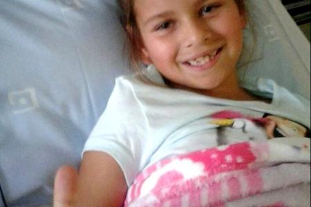  â€˜n Moedige klein Carli Swart (7) wys hier met haar duim opwaarts vanuit haar hospitaalbed in die Louis Leipoldt Hospitaal dat sy sommer baie goed voel na die vorige dag se operasie. 