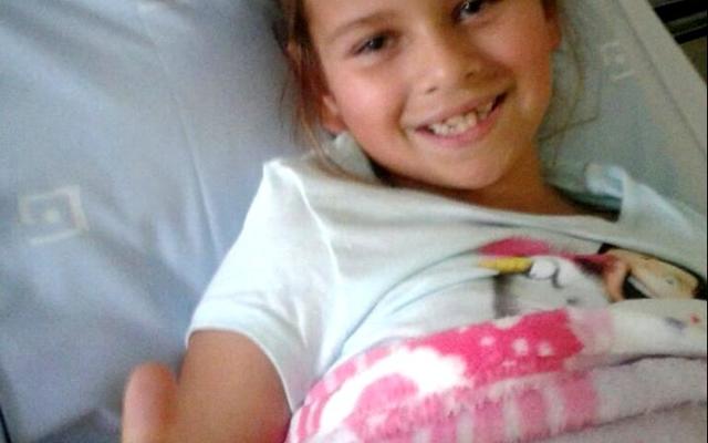  â€˜n Moedige klein Carli Swart (7) wys hier met haar duim opwaarts vanuit haar hospitaalbed in die Louis Leipoldt Hospitaal dat sy sommer baie goed voel na die vorige dag se operasie. 